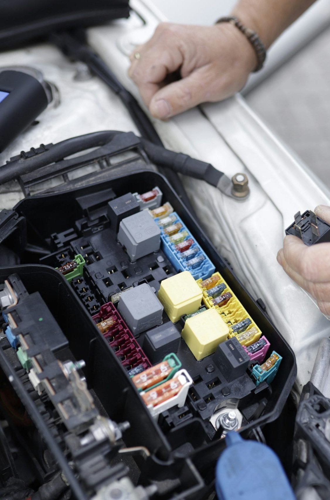 image of a mechanic inspecting a fuse box in a car