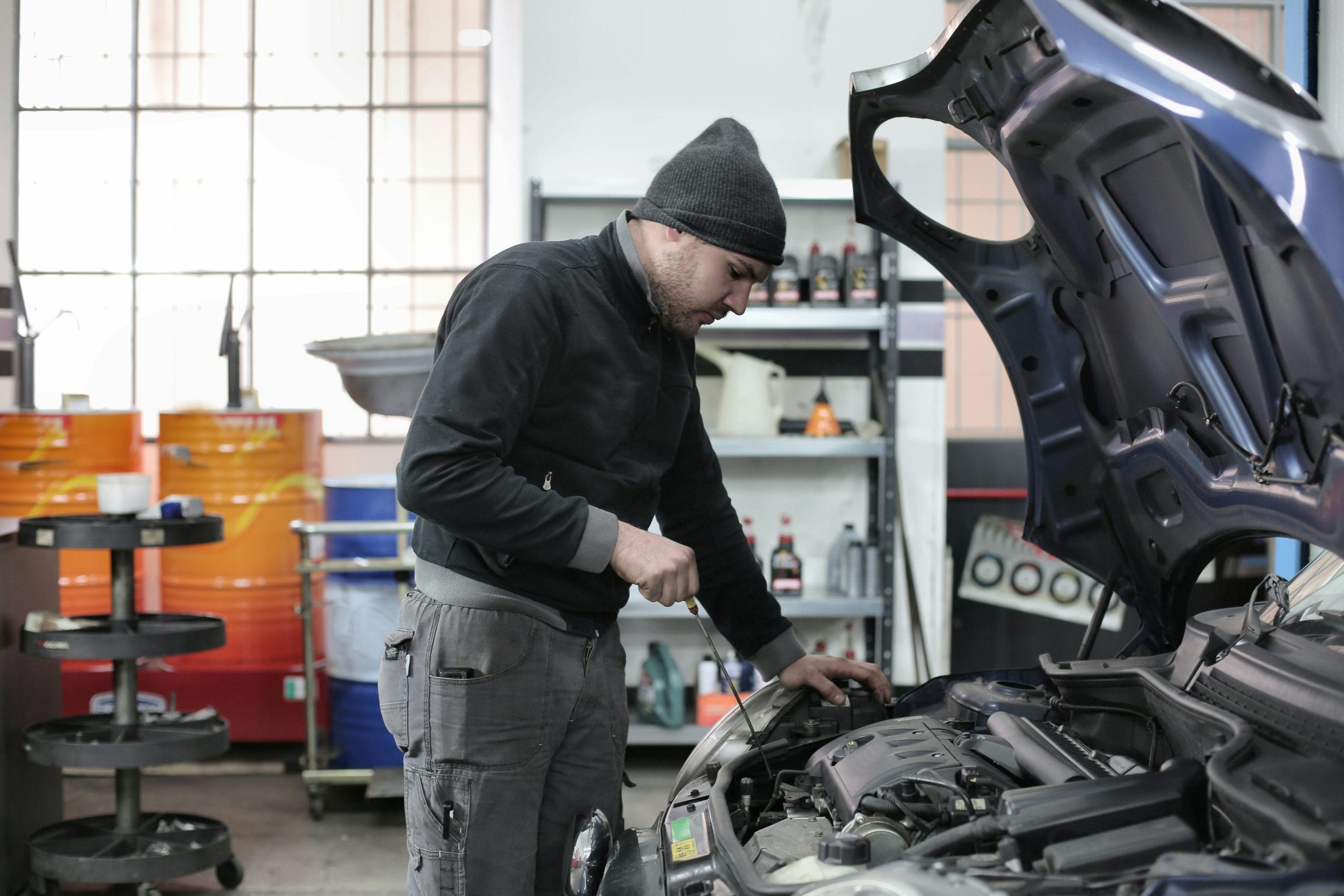 image of a mechanic checking on oil in cars engine